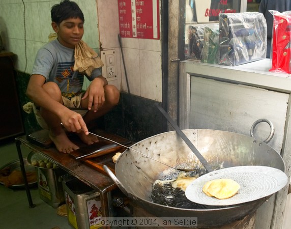Young boy frying food in a large wok, Old Delhi