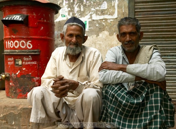 Two old men sitting beside a bright red post box, Old Delhi