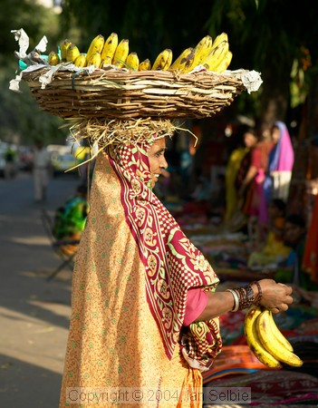 Woman selling bananas from a basket on her head at the textiles market