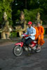 Motorcyclist carrying two monks crossing  the Rainbow Bridge at the South Gate of Angkor Thom