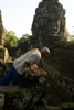 Old man looking down under the watching eyes of one of the faces of the Bayon