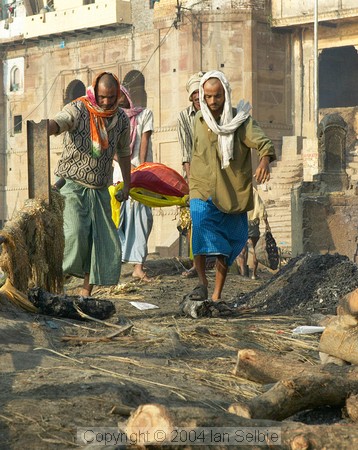 At Manikarnika Ghat, a corpse is carried down to the cremation area