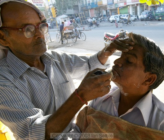 Roadside barber lathers up his customer, Jaipur