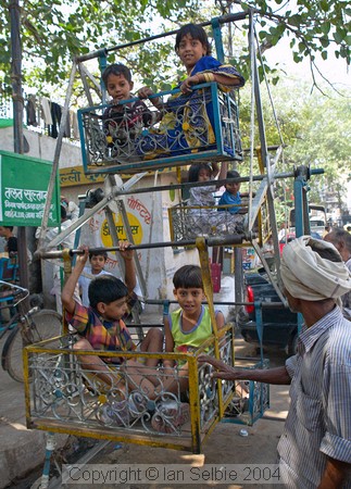 Children having a ride on a hand operated ferris wheel, Chandni Chowk, Old Delhi