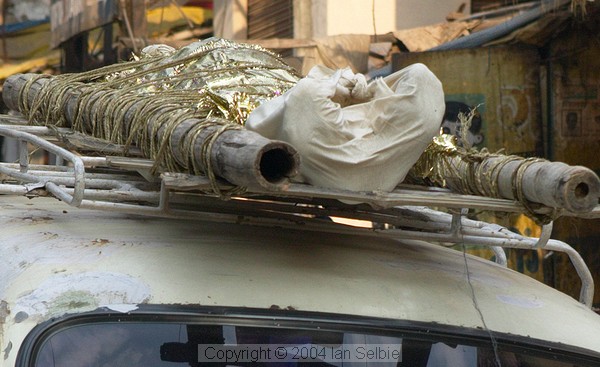 A corpse arrives at Harishchandra Ghat tied on top of an Ambassador car