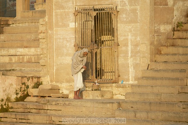 Old man climbing the steep sandstone steps of the ghats
